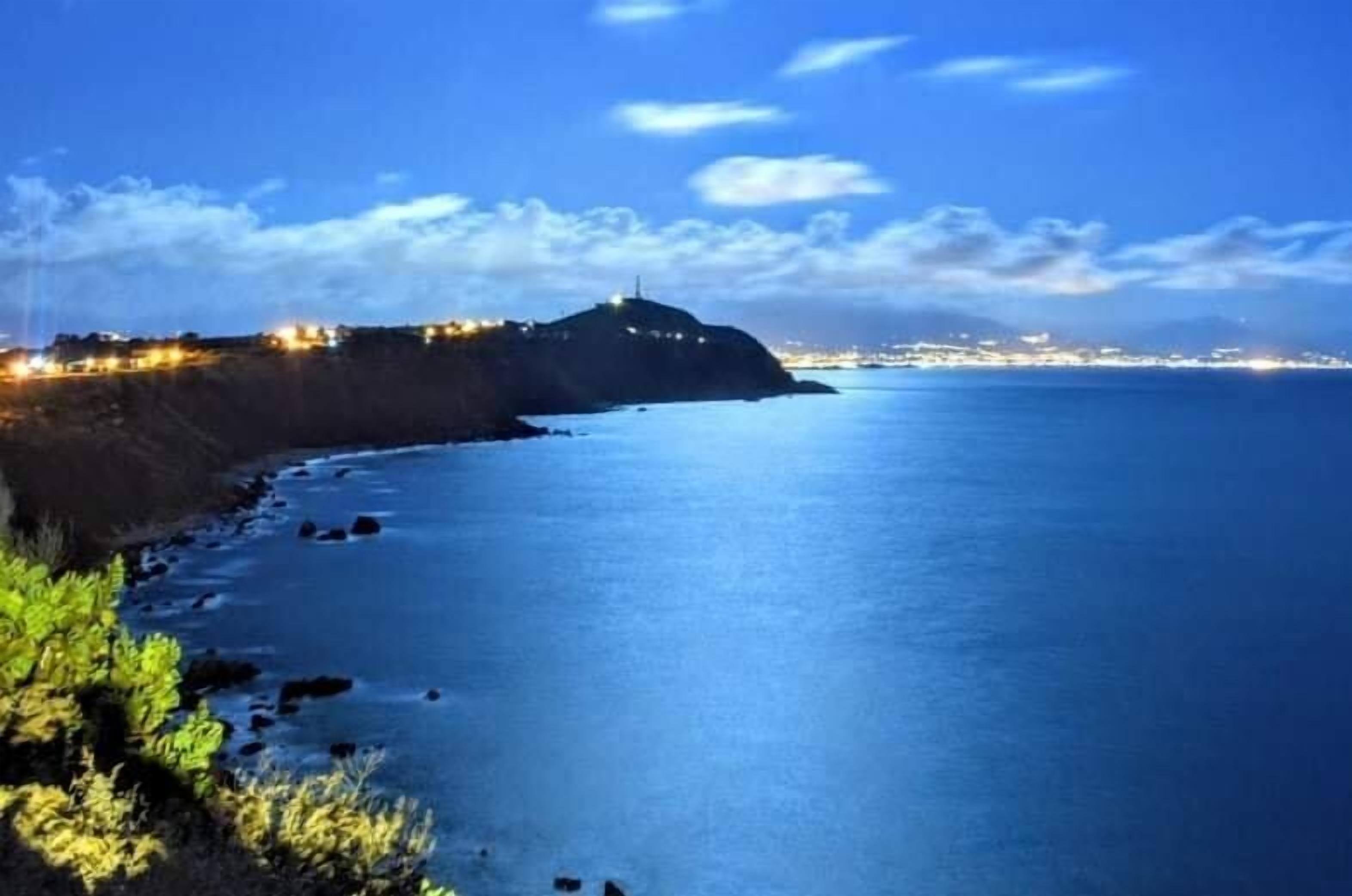 A coastal landscape with a prominent hill and a calm sea.