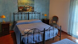 A bedroom with a bed, two bedside lamps, a chair, a painting on the wall, and a window with curtains.