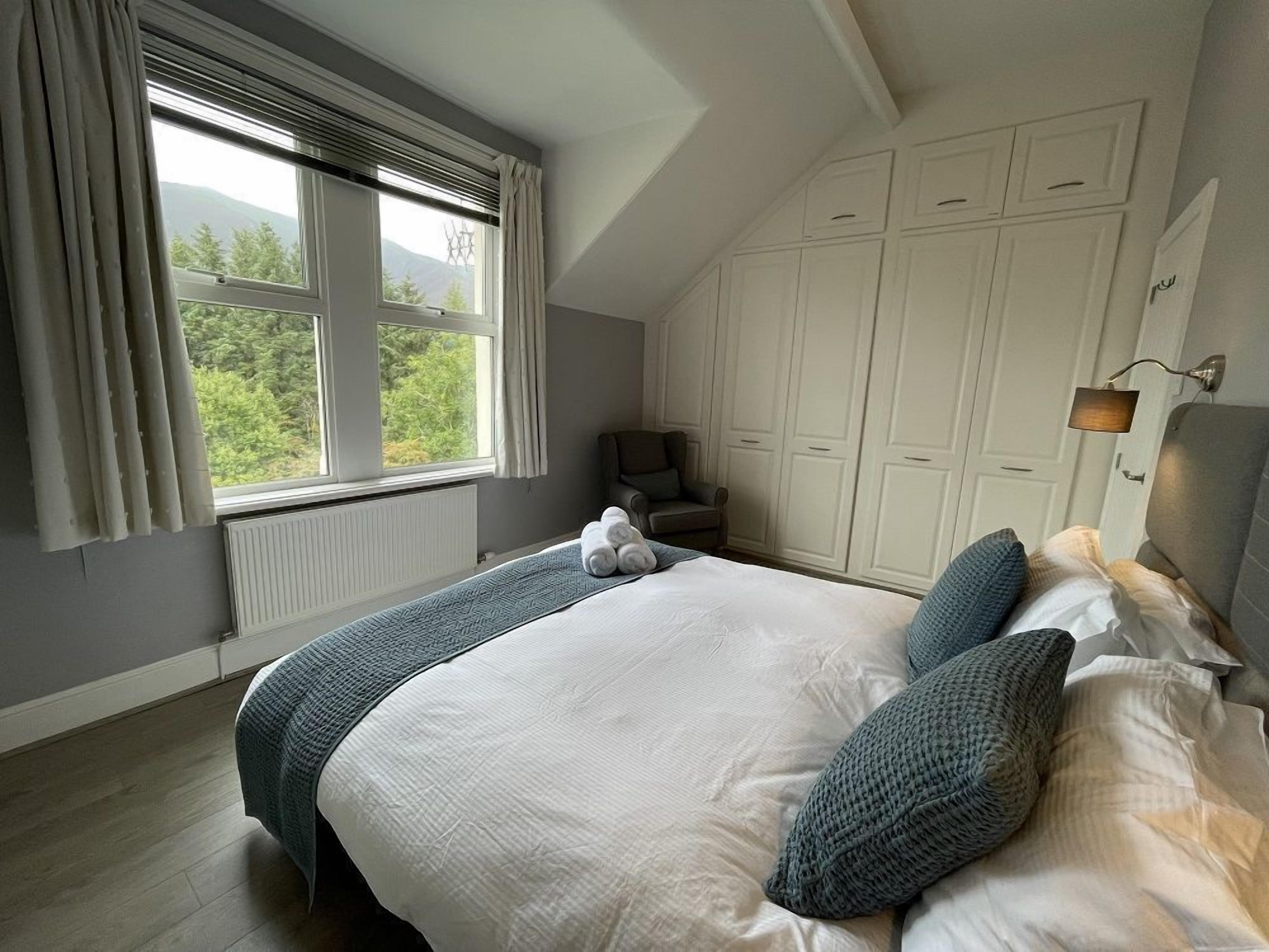 A bedroom with a large bed, a chair, and a wardrobe.