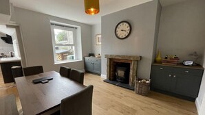 Una cocina moderna con chimenea, piso de madera y un comedor con mesa y sillas.