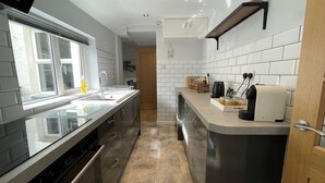 Una cocina moderna con una isla grande, electrodomésticos de acero inoxidable y paredes de azulejos blancos.
