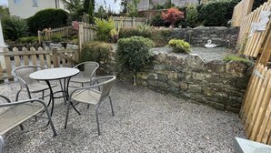 Un espace patio agrémenté d’un mur en pierre, d’une clôture en bois et d’une table avec des chaises.