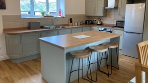 Een moderne keuken met een centraal eiland, een paar barkrukken en een inbouwoven.