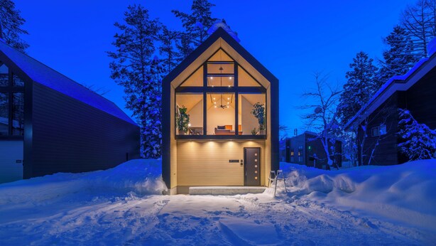 Ein gemütliches Blockhaus mit warmer Einrichtung, umgeben von schneebedecktem Boden und Bäumen.