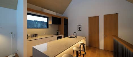 Una cocina moderna con una isla grande, taburetes de bar, una ventana y suelo de madera.