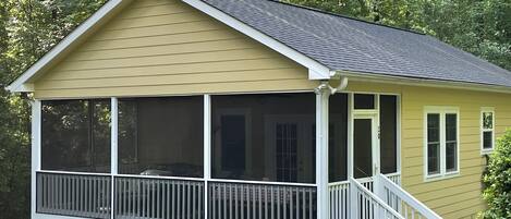 Een gelijkvloers huis met een veranda, een kamer met hor en een kleine voortuin.