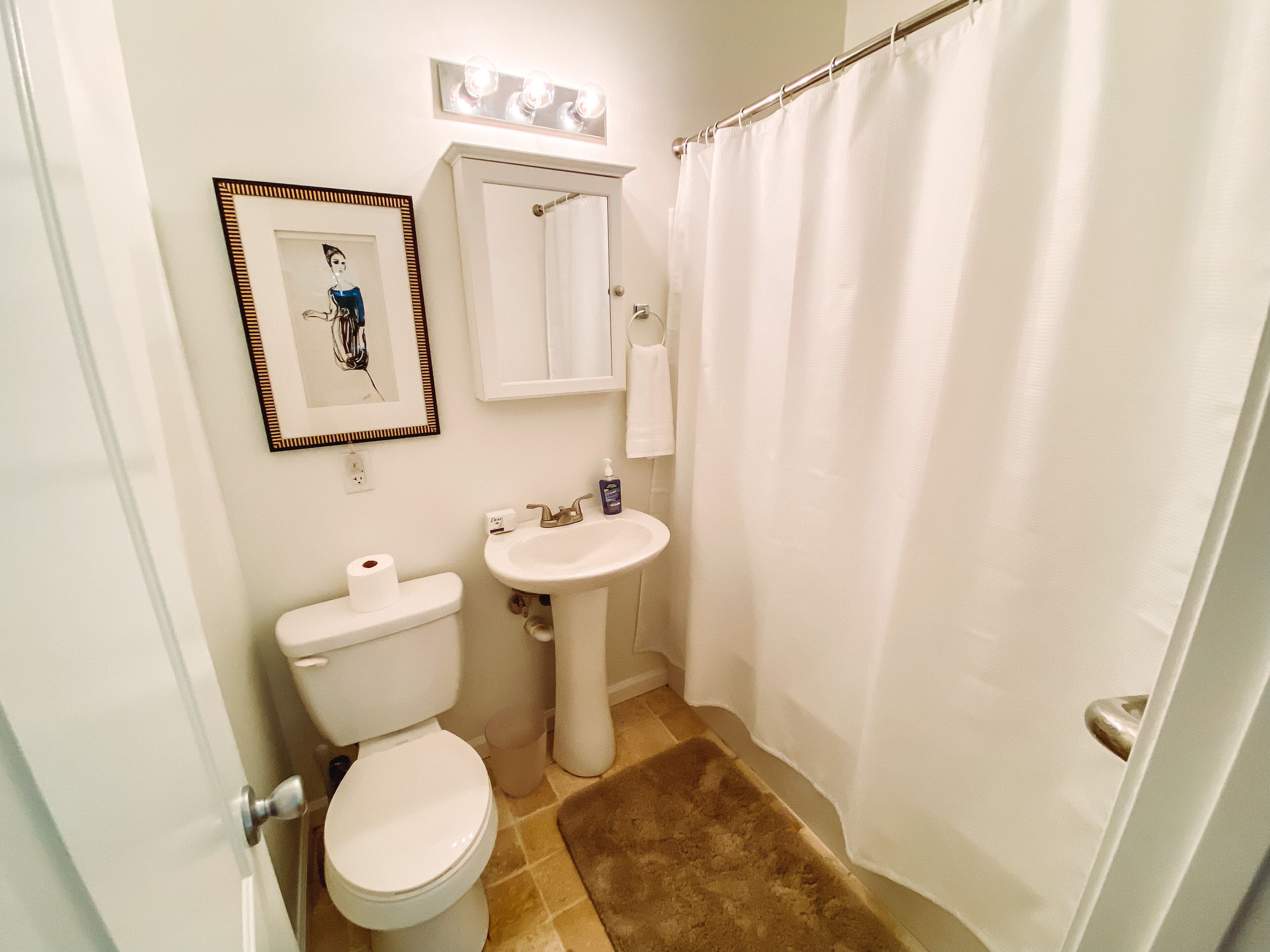 A bathroom with a toilet, sink, and shower curtain.