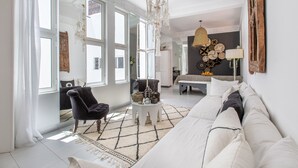 Ein modernes Wohnzimmer mit einem großen Sofa, einem schwarzen Sessel, einem weißen Couchtisch und einer Kristallleuchtre.