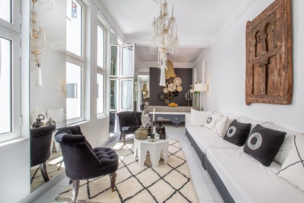 A modern living room with a sofa, armchairs, a coffee table, and a chandelier.