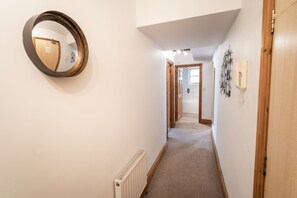 Stylish hallway with a round mirror and radiator, leading to a door with a small window.