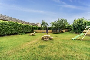 Enjoy an and inviting backyard with a lawn, play structure, picnic tables, and seating area.