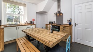 Een moderne keuken met een houten tafel, een bank en een inbouwoven.