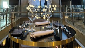 A modern dining area with a high ceiling, exposed beams, and a central chandelier. - Loly Boutique Hotel (Rome)