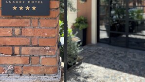 A brick wall with a sign for the Lolly Luxury Hotel. - Loly Boutique Hotel (Rome)