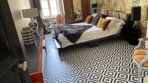 A bedroom with a bed, bedside table, lamp, and patterned floor.