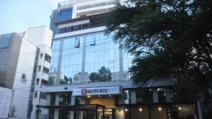 A hotel with a modern glass facade, a sign reading "MASTIFF HOTEL", and a gated entrance.