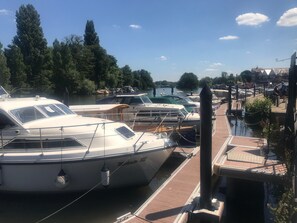 Un port de plaisance avec plusieurs bateaux amarrés, une passerelle en bois et un ciel dégagé.