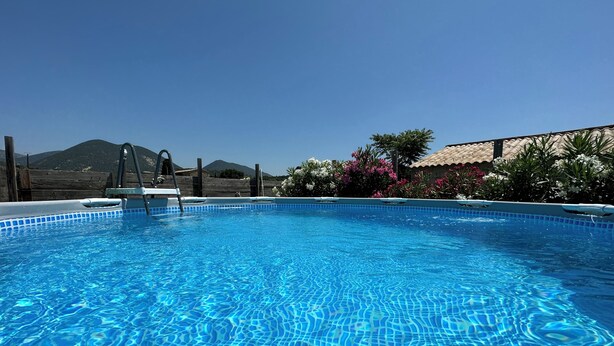 A clear blue pool with a ladder, surrounded by plants and a mountain in the background. - Gîte Mobil-home in Drôme Provençale (Saint-Pantaléon-les-Vignes)