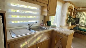 A compact kitchen with wooden cabinets, a sink, and a countertop. - Gîte Mobil-home in Drôme Provençale (Saint-Pantaléon-les-Vignes)