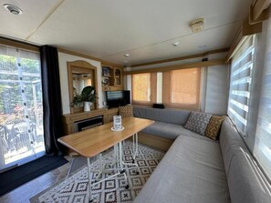 A compact living space with a sofa, a small table, a television, and a window with blinds.