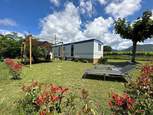 Une maison mobile dotée d’un patio, d’une table et de chaises.