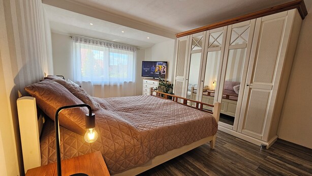 A bedroom with a bed, bedside lamp, wardrobe, and a TV on a dresser. - Fe-Wo Gold-Blick*** (Korbach)
