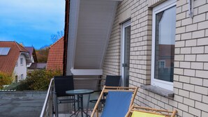 A balcony with two folding chairs, a table, and a window. - Fe-Wo Gold-Blick*** (Korbach)