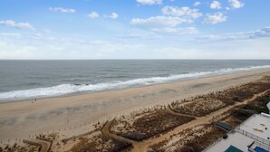 Ein Strand mit einer Umzäunung, einem Weg und einem Gebäude mit blauem Dach.