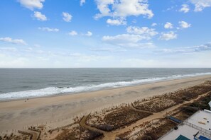 A beach with a fence, a path, and a building with a blue roof.