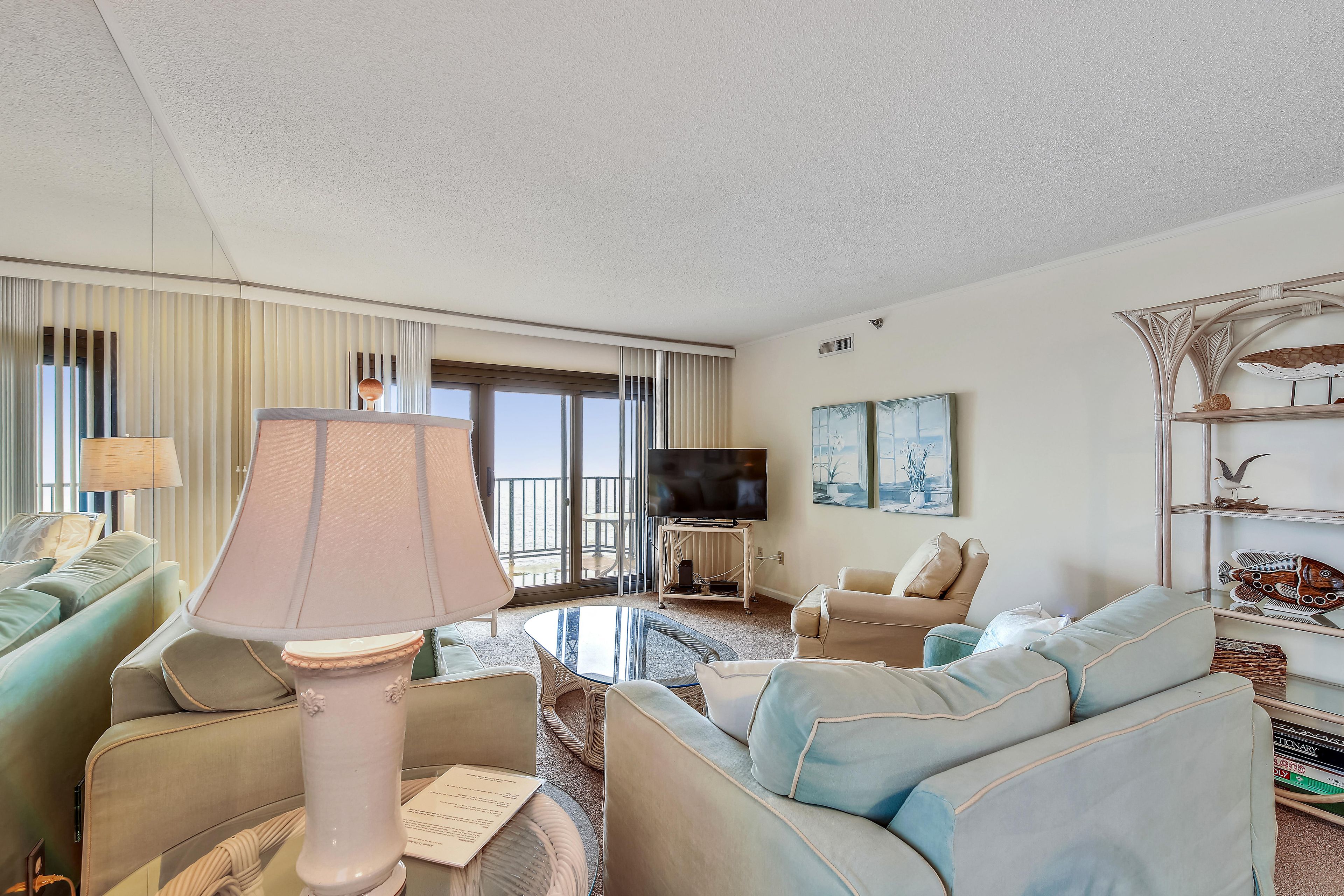Een hotelkamer met een bank, fauteuils, een televisie en een balkon met uitzicht.