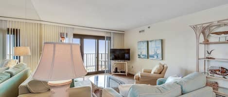 Een hotelkamer met een bank, fauteuils, een televisie en een balkon met uitzicht.