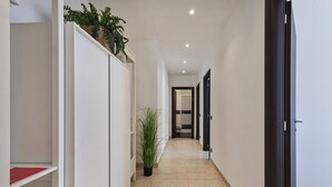 A narrow hallway with a white wardrobe, a potted plant, and a door leading to a bathroom. - Shelley Apartments - Sun by Wonderful Italy (Genova)