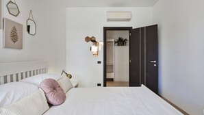 A bedroom with a bed, bedside lamp, and a wardrobe. - Shelley Apartments - Sun by Wonderful Italy (Genova)