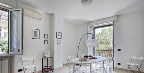 A modern, well-lit room with a round table and clear chairs, a standing lamp, and framed inspirational quotes on the wall.
