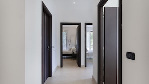 Un corridoio con porte in legno scuro che conducono a una stanza con un letto e una finestra.