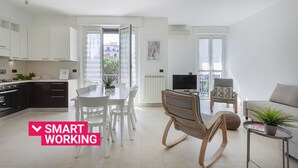 Un appartamento moderno con cucina, zona pranzo e soggiorno, dotato di balcone e televisore.