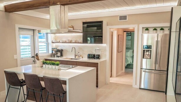 A modern kitchen with a central island, stainless steel appliances, and a view to the outside.