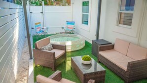 A patio area with wicker furniture, a round hot tub, and a small table with a bowl.