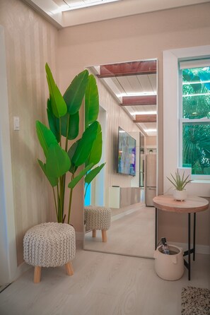 Reflecting elegance, this room features a large mirror, a potted plant, and a round table with a stool.
