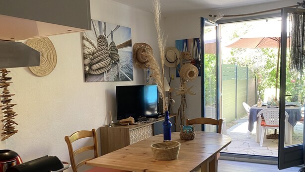 A dining area with a wooden table, chairs, a TV, and a view of the outdoors.