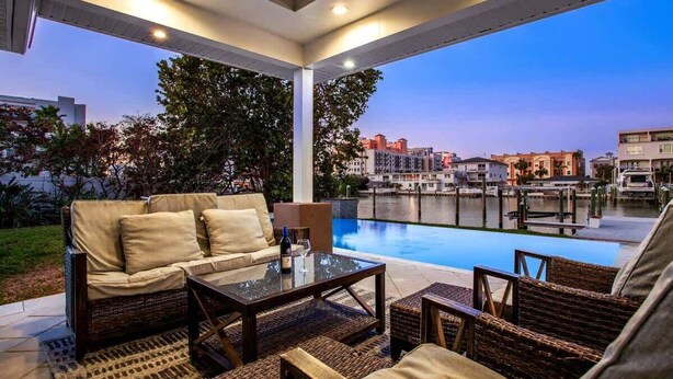 Une terrasse extérieure avec une piscine, des meubles en osier et une vue sur le paysage urbain.