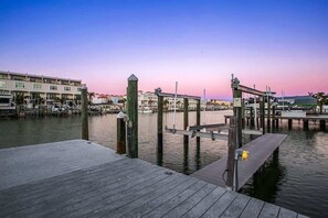 Un port de plaisance avec des quais en bois, un bâtiment doté de nombreux balcons et un ciel dégagé.