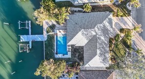 Vue aérienne d’une propriété dotée d’une piscine, d’un quai et d’un espace verdoyant.