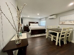 Relax in a stylishly designed room with a comfortable bed, dining area, and natural light pouring in through the large window.