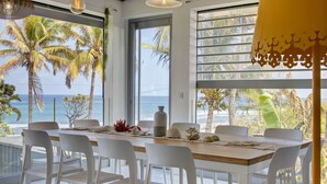 A dining area with a view of the ocean, white chairs, a wooden table, and decorative items. - Villa Raj Mahal, 2 minutes from the beach (Saint Paul)