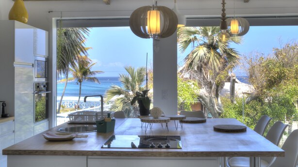 A kitchen with a large island, a view of the ocean, and a dining area with chairs and a table. - Villa Raj Mahal, 2 minutes from the beach (Saint Paul)