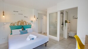 A modern hotel room with a bed, a shower area, and a yellow chair. - Villa Raj Mahal, 2 minutes from the beach (Saint Paul)