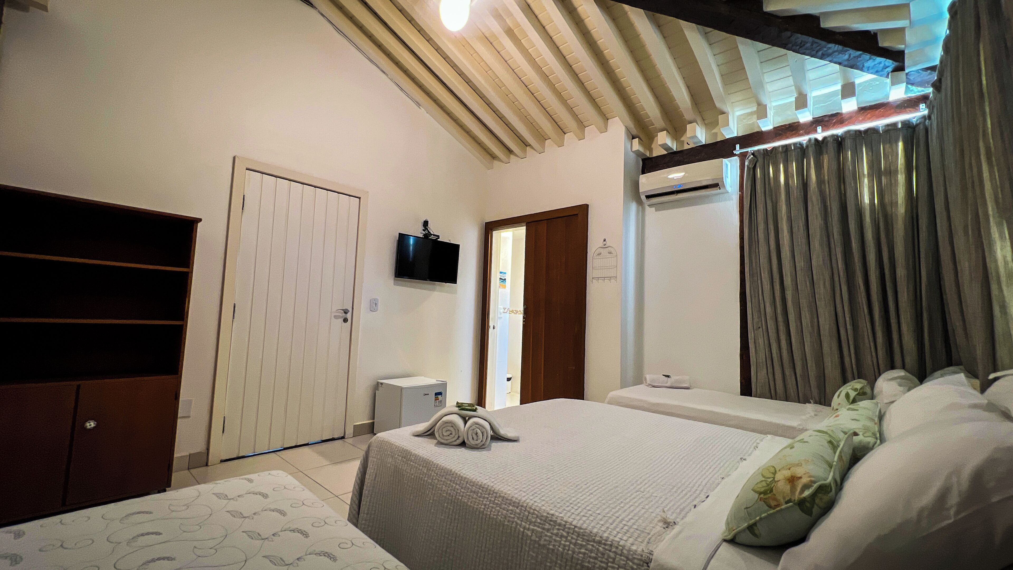 Un dormitorio con cama, armario, televisor montado en la pared y aire acondicionado.