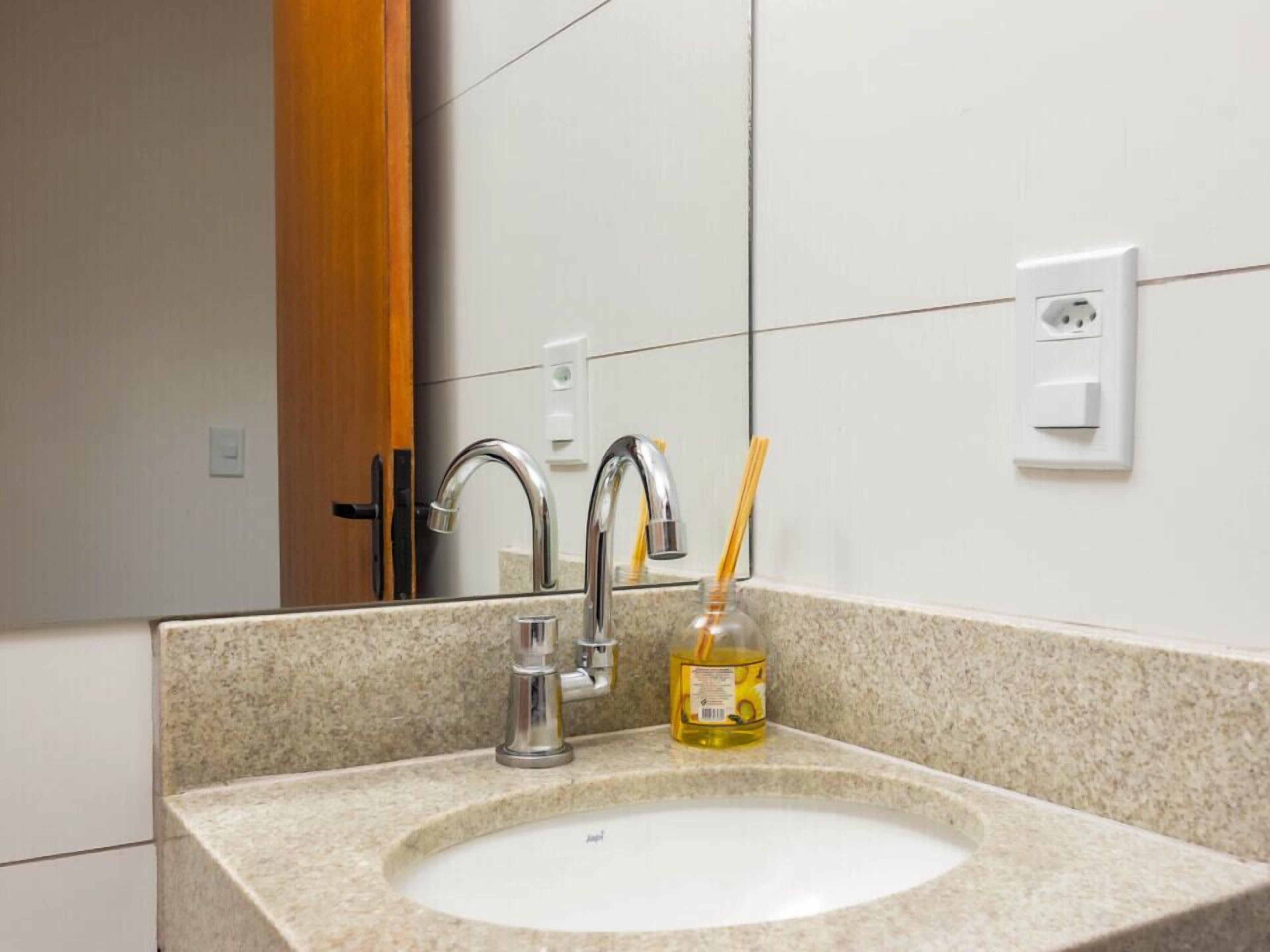 A bathroom sink with a mirror, a faucet, and a bottle of hand soap.