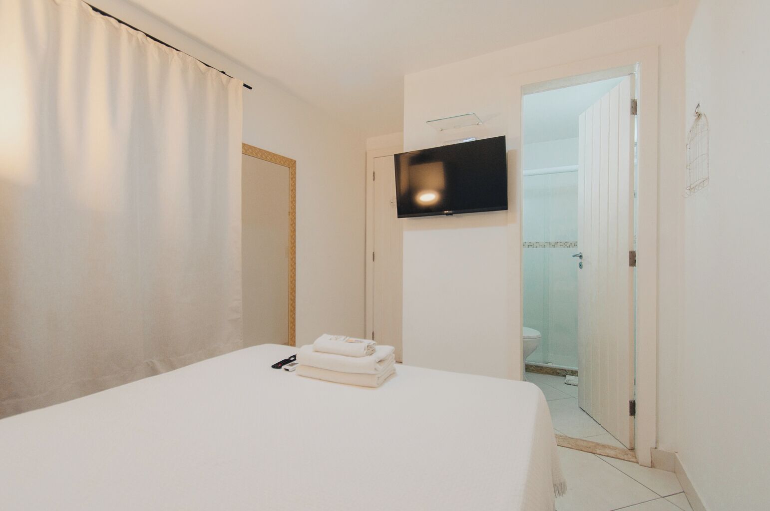 A hotel room with a bed, a TV mounted on the wall, and a door leading to a bathroom.